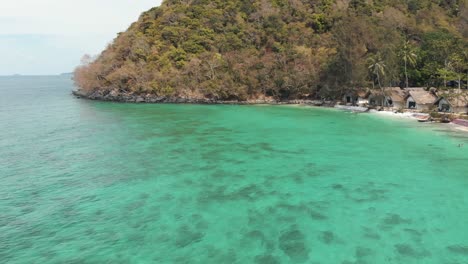 Beautiful-transparent-emerald-shallow-shore-on-Coral-Island-,-Thailand---Aerial-low-angle-panoramic-shot