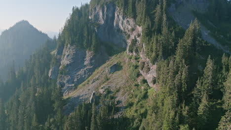 Aerial-footage-flying-close-to-the-peak-of-a-mountain-showing-trees-in-the-rock-in-the-morning-haze-in-the-Cascade-Mountains-in-Washington