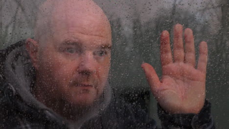 A-depressed-lonely-man-feeling-isolated-looking-through-a-window-in-the-rain