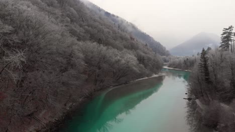 Die-Drohne-Fliegt-An-Einem-Kalten,-Nebligen-Wintermorgen-Tief-über-Dem-Sauberen-Smaragdgrünen-Fluss