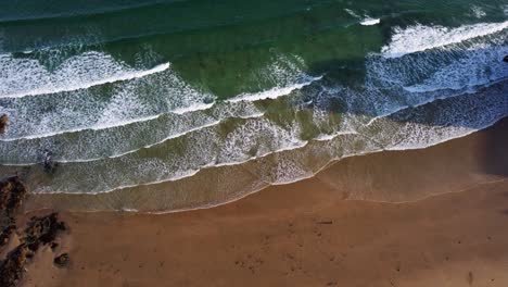 Static-aerial-looking-down-shot-of-waves-hitting-the-beach-in-the-morning,-Newquay,-Cornwall,-England,-Uk