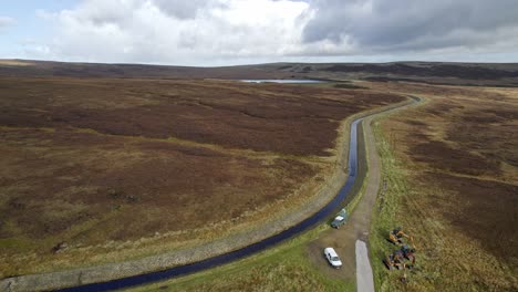 Drone-video-footage-of-a-reservoir-and-overflow-system-in-the-Saddleworth-moors-in-West-Yorkshire-UK,-Showing-work-vehicles-and-plant-machinery