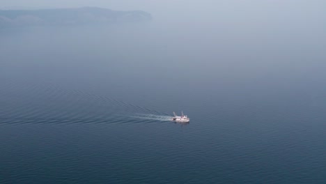 Fishing-boat-traveling-on-calm-blue-sea-in-morning,-aerial