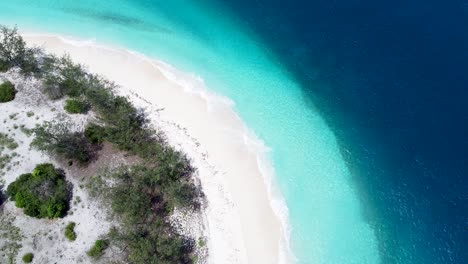 Uninhabited,-remote,-idyllic-tropical-island-paradise-with-curved-white-sandy-beach,-shallow-crystal-clear-water-and-deep-blue-ocean-on-Jaco-Island,-Timor-Leste