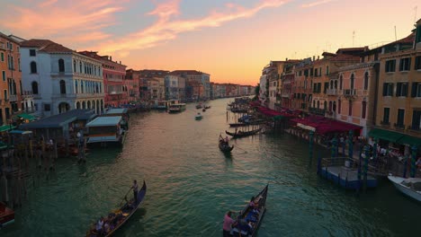 Grand-canal,-Canale-Grande-in-Venice,-Italy-by-sunset-with-boats-and-gondola,-old-houses-and-a-cathedral-close-to-San-Marco-and-Rialto-Bridge