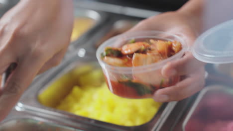 Placing-Kimchi-In-A-Round-Plastic-Food-Container-For-Takeaway