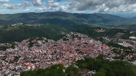 City-and-the-Jesus-statue-of-Taxco-Guerrero,-Mexico---rotating,-overlook,-aerial-view