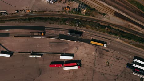 Aerial-view-above-a-trucks-passing-a-entrance-point-at-a-shipping-terminal---top-down,-drone-shot