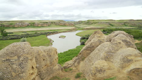 Writing-on-Stone-Provincial-Parks-bandlands-and-Hoodoos-with-river-in-a-desert-in-Alberta,-Canada-during-overcast-day
