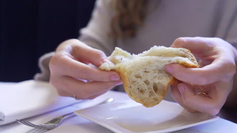 Woman's-hands-tearing-bread-at-a-restaurant-table