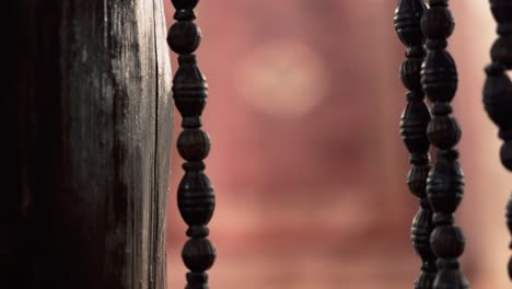 A-close-up-shot-of-wooden-beads-curtain-transition-to-a-carpet-on-the-wall,-hotel-restaurant-in-Agra,-India
