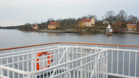 Moving-shot-from-the-Stockholm-archipelago-boat-tour-watching-the-view-of-houses-and-a-boat-in-front-of-the-wide-ocean-water-on-a-bright-day-out