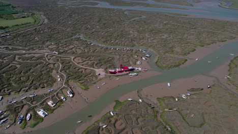 Aerial-view-over-the-stranded-LV15-Trinity-Lightvessel,-sunny-Tollesbury,-UK---tilt,-drone-shot