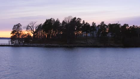 Slow-motion-shot-of-the-beautiful-landscape-of-trees-and-the-sunset-on-the-running-water-at-one-of-Stockholm's-Archipelago-islands
