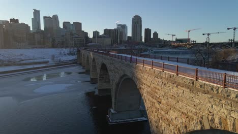 Aerial-view-of-Stone-Arch-bridge-in-Minneapolis,-MN-during-golden-hour-winter-afternoon