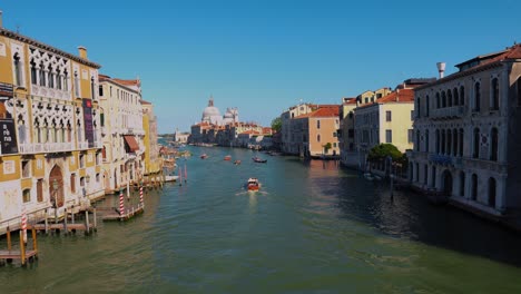 The-Grand-canal,-Canale-Grande-in-Venice,-Italy-with-a-boat-and-gondola,-old-houses-and-a-cathedral-church-close-to-San-Marco-and-Rialto-Bridge