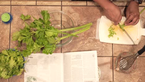 Overhead-view-of-a-homemaker-chopping-organic-celery-for-ingredients-in-a-homemade-recipe---slow-motion