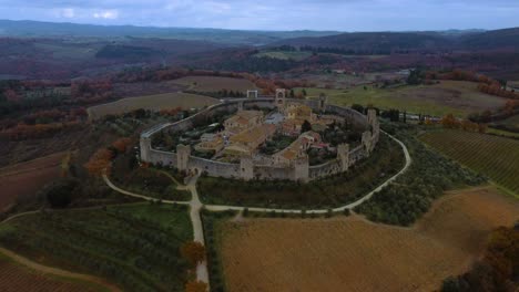 Monteriggioni-is-an-ancient-old-medieval-walled-fortification-town-near-iconic-Siena-and-Florence-in-Tuscany,-Italy-near-Chianti-wine-and-vinery-area,-seen-from-above-by-drone-as-aerial-view-in-4K
