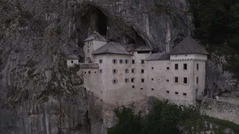 Drone-video-of-a-crane-plane-descending-over-the-Rredjama-castle-in-Slovenia-with-people-coming-out-of-the-interior