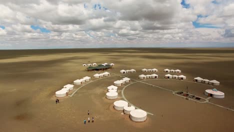 Aaerial-flying-across-white-nomad-tent-camp-in-the-middle-of-huge-sandy-desert