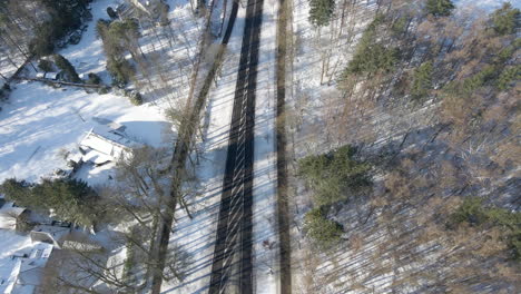 Top-down-aerial-of-empty-road-running-through-forest-in-winter