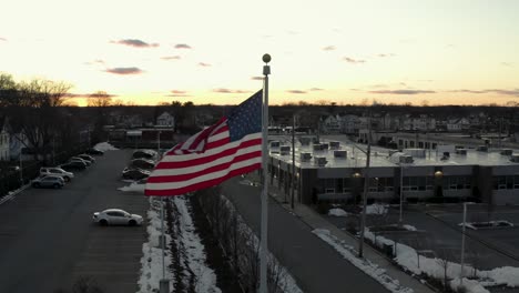 Umkreisen-Einer-Amerikanischen-Flagge,-Die-Bei-Sonnenuntergang-Im-Wind-Weht---Parallaxe-Luftaufnahme