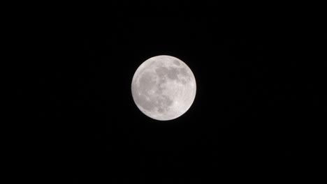 Close-up-shot-of-full-moon-set-against-dark-black-night-sky-in-slow-motion