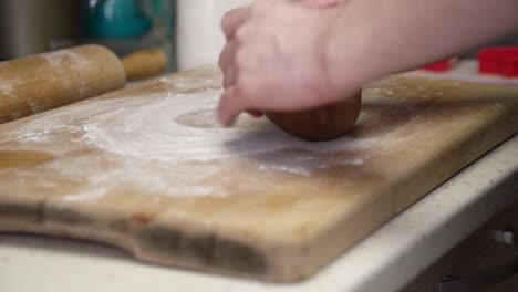 Caucasian-woman-dusting-wooden-board-and-working-on-gingerbread-dough-with-a-rolling-pin