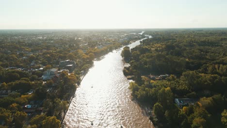 Luftaufnahme-Des-Flusses-Lujan-Mit-Häusern-Und-Bäumen-An-Den-Seiten-Nahe-Der-Sonnenuntergangszeit