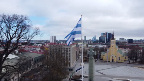 Bandera-De-La-Ciudad-De-Tallin-Ondeando-En-El-Viento,-Fondo-De-Paisaje-Urbano