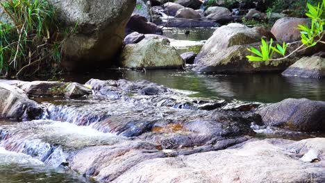 Crystal-clear-shimmering-water-flowing-in-rough-rocky-stream-bed-close-up
