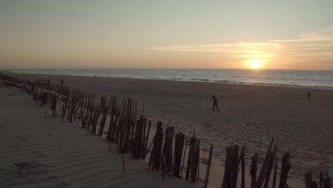 Wide-shot-of-the-sunset-on-the-beach-of-Sylt-with-people-walking-by