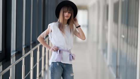 attractive-young-girl-in-a-hat-with-a-waist-bag-posing-taking-off-her-hat