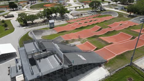 drone-view-of-a-BMX-track-and-a-long-jump-by-a-bicycle-rider-after-launch-starting-from-the-ramp