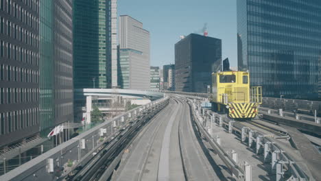 A-Point-of-view-shot-of-the-Yurikamome-Monorail-slowing-moving-between-skyscrapers-in-Tokyo,-Japan