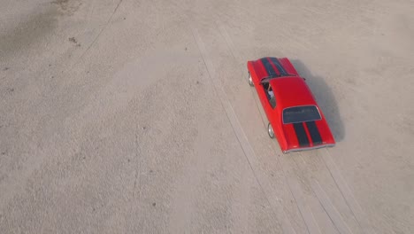 From-the-top-view-of-an-old-American-muscle-car-in-a-dirt-road-during-a-sunset