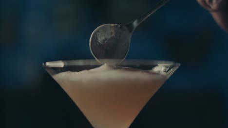 Milchcreme-Mit-Teelöffel-In-Cocktailglas-Geben