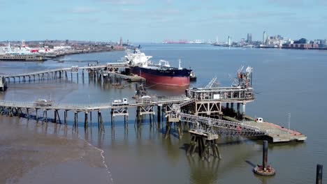 Crude-oil-tanker-ship-loading-at-refinery-harbour-terminal-aerial-view-reverse-zoom-out-to-wide