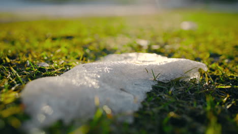 Last-piece-of-snow-on-a-green-lawn,-sunny-spring-day---circling,-closeup-view