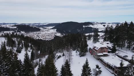 Ski-center-town,-aerial-shot-with-hotels,-houses,-trees,-panoramic-view,-everything-covered-with-snow