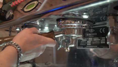 Barista's-Hand-Putting-Back-Portafilter-To-Coffee-Machine-In-Cafeteria