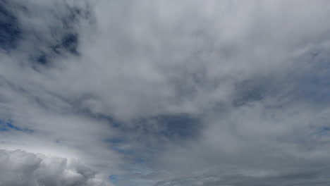 Rain-clouds-emerge-in-sky-on-clear-day,-long-shot-time-lapse