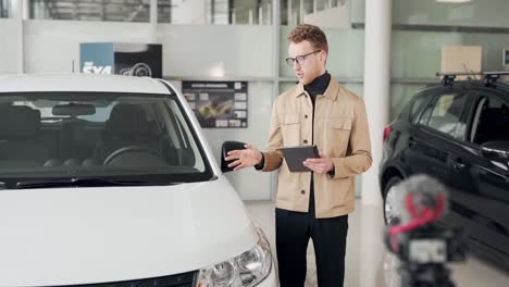 Handsome-man-shoots-a-video-presentation-of-the-car-in-a-car-dealership