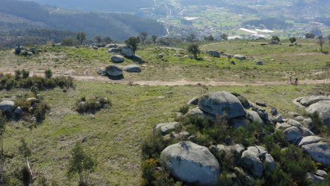 Aerial-tracking-cyclists-riding-through-Alto-Minho-mountain-top,-Portugal---Slide-shot