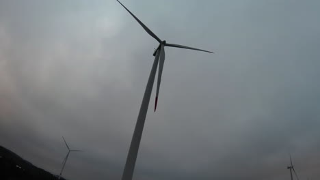 Windkraftanlage,-Die-Sich-Unter-Bewölktem-Himmel-Dreht,-Niedriger-Winkel-Fpv
