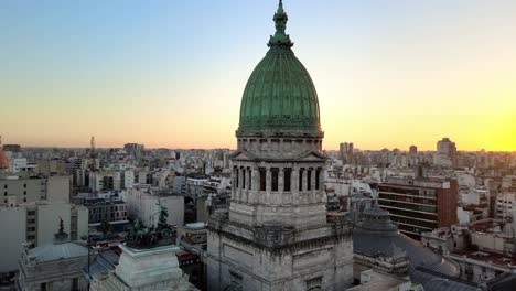 Aerial-orbit-around-Argentine-Congress-building-green-bronze-dome-tower-at-sunset-in-Balvanera-neighborhood,-Buenos-Aires