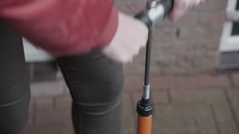 Dame-Pumpt-Draußen-Eine-Fahrradreifenpumpe,-Um-Sicherzustellen,-Dass-Ihre-Fahrradreifen-Ausreichend-Luftdruck-Haben