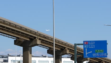 Monorail-and-plane-taking-off-in-background,-outskirts-of-Haneda-airport