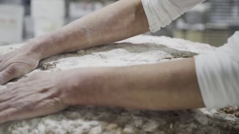 Close-up-shot-of-men-hands-of-a-baker-spreading-flour-evenly-on-a-dough-for-sweets-in-a-sweets-factory-in-medina-sidonia