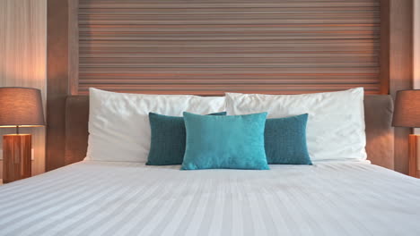 Slow-pan-right-on-the-made-up-bed-with-white-and-turquoise-color-pillows-in-a-hotel-resort-in-Thailand